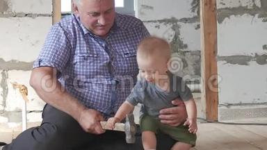 在工地上工作的爷爷和孙子。祖父教他的孙子锤钉子